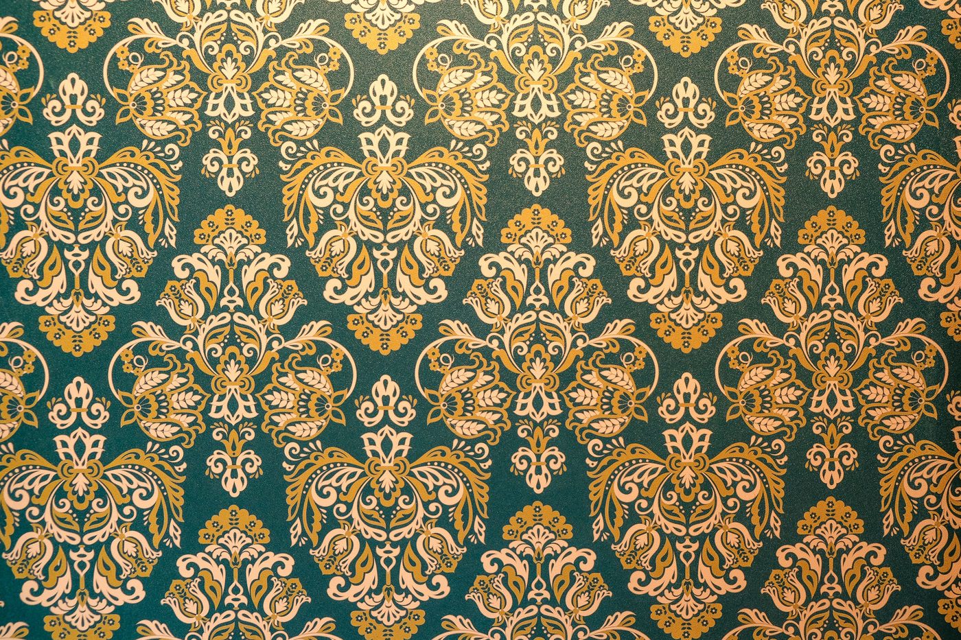 Close-up of teal wallpaper with an ornate gold and cream damask pattern